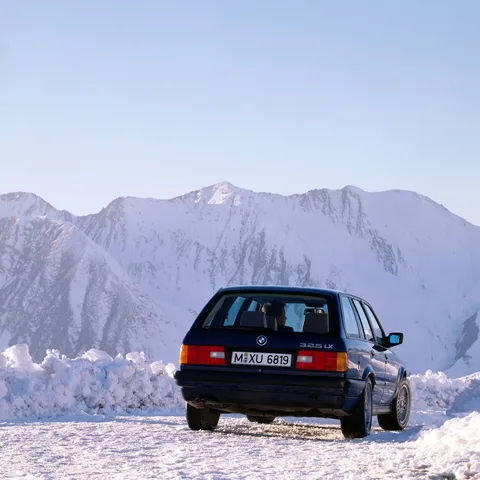Dark blue BMW E30 325iX Touring parked in snowy mountains