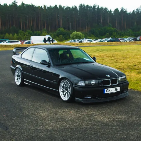 Black BMW E36 3 Series coupé parked on a track apron
