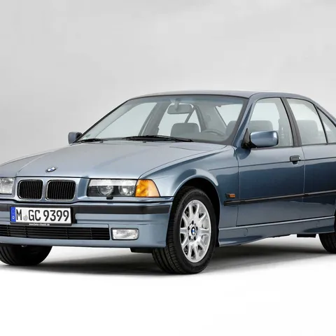 Blue-grey BMW E36 3 Series four-door saloon, studio front three-quarter shot