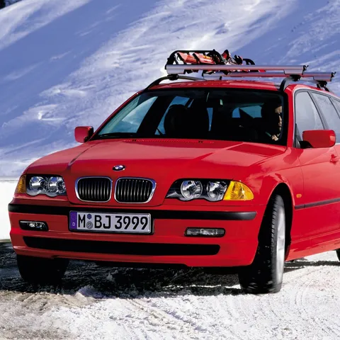 Red BMW E46 3 Series Touring with a roof rack driving in snow