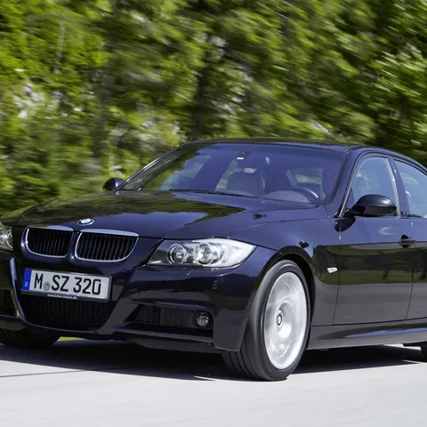 Dark blue BMW E90 3 Series saloon driving on a country road