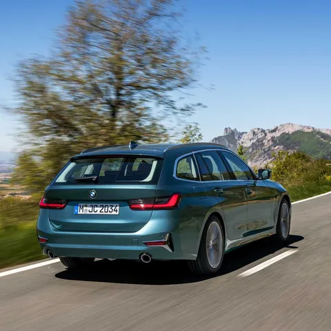 Blue-green BMW G21 3 Series Touring driving, rear three-quarter view